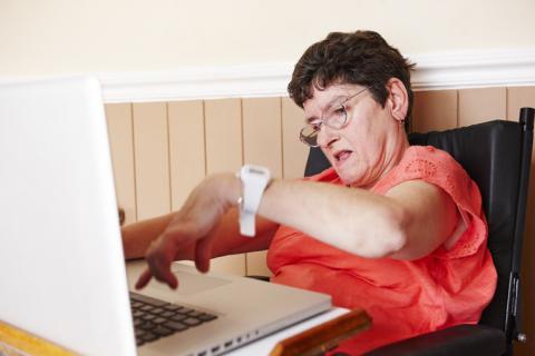 A woman with short hair and glasses typing on a laptop