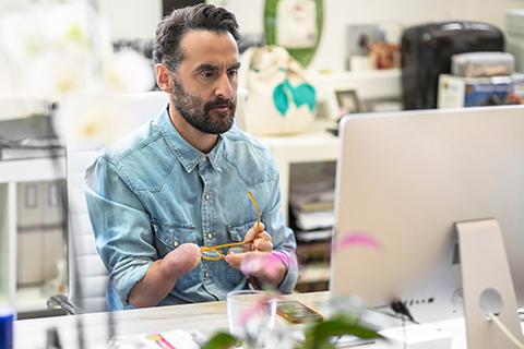 Man with a partially amputated right arm working at a computer